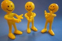 three yellow happy face heads with bodies clapping